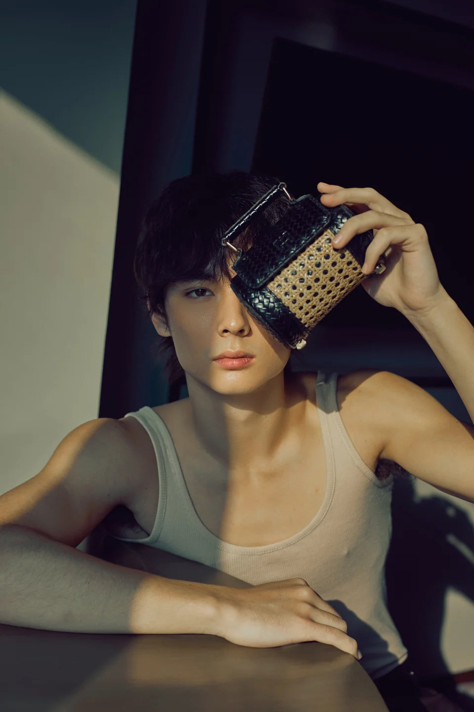 Close portrait of a model holding a Black Weave Solihiya Rollers Mini, showing its woven leather and cane panels.