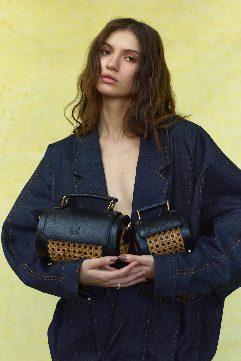 Two black Solihiya Roller bags with woven panels, worn with a navy jacket