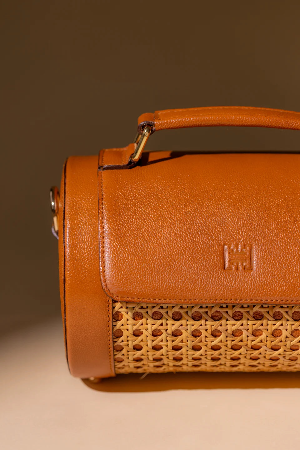 Close-up of the tan leather flap, top handle and woven cane panel of the Solihiya Rollers Regular.